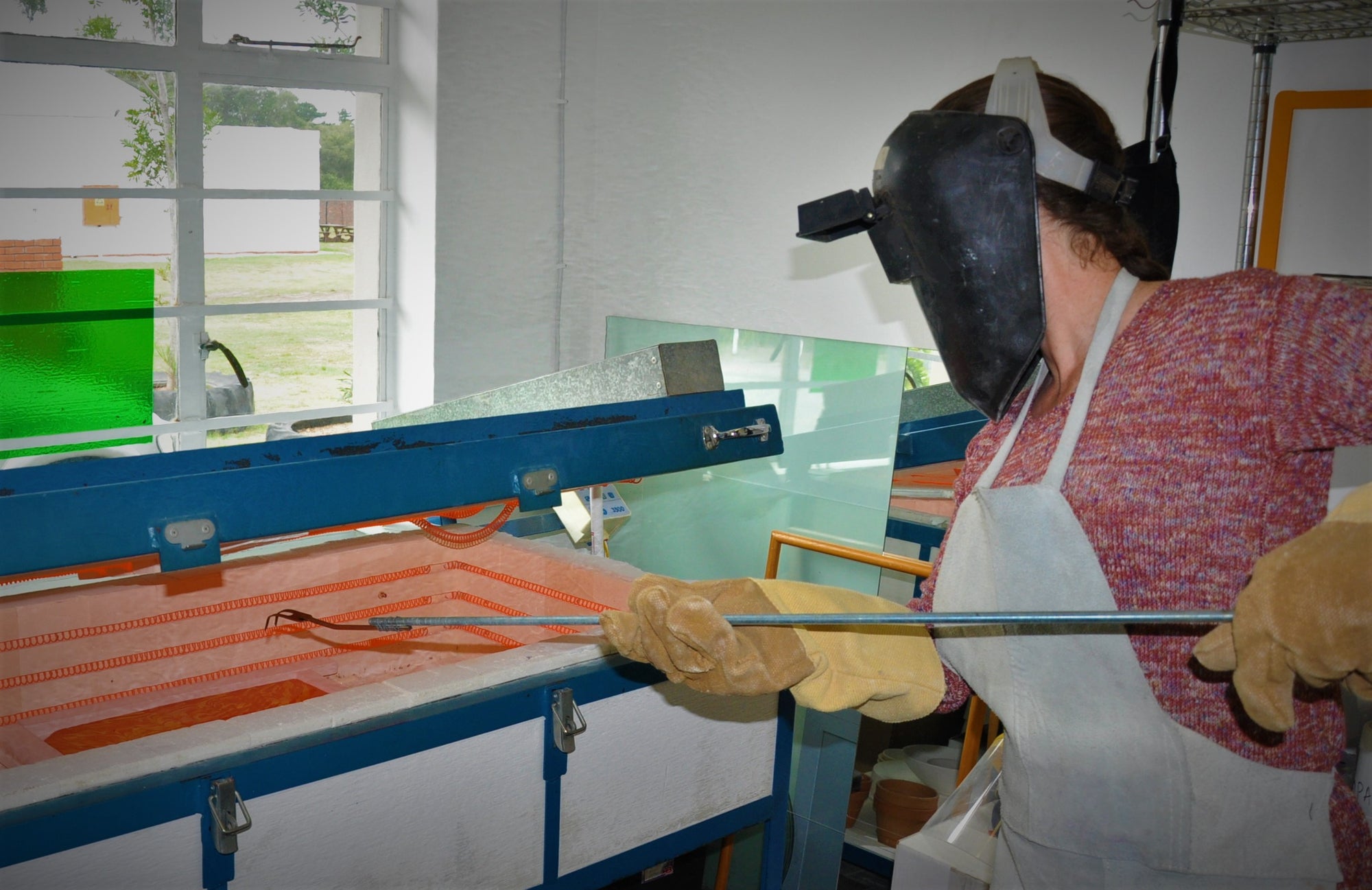 glass artist Helga Stassen combing fused glass art in a kiln in her studio in Sedgefield, South Africa